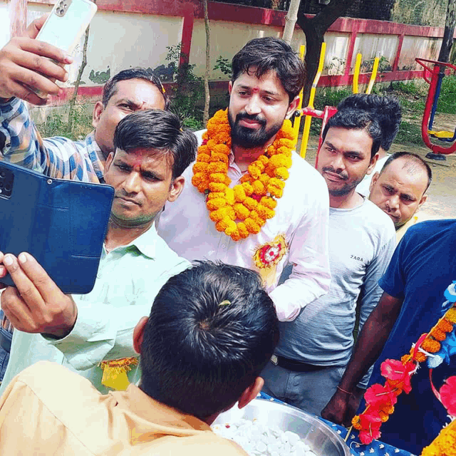 a man wearing a floral garland takes a selfie