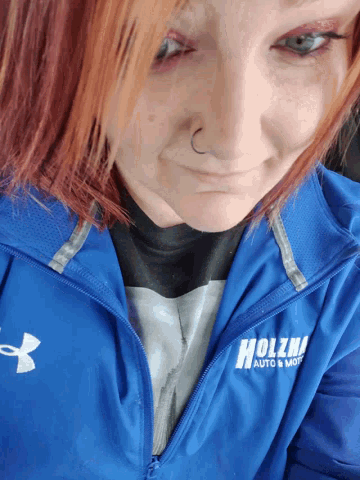 a woman wearing a blue jacket that says holzwi auto & more on it