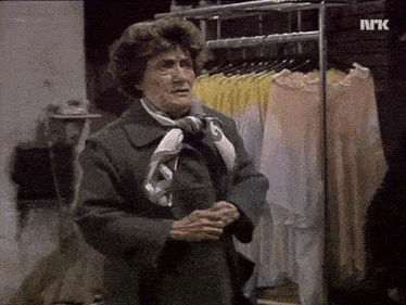 a woman is standing in front of a rack of clothes with the letters nrk on the bottom