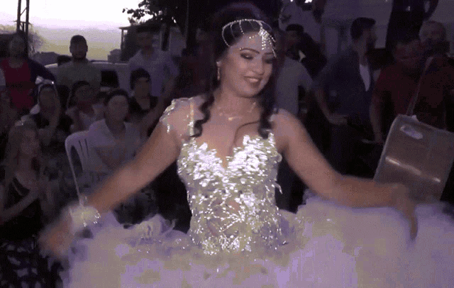 a woman in a white dress is dancing in front of a crowd of people