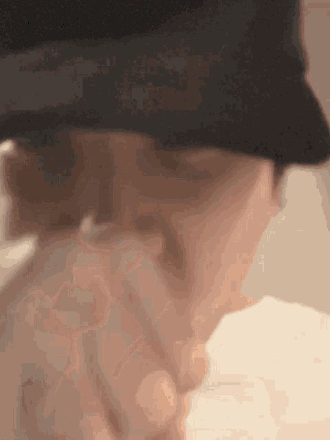 a close up of a person wearing a hat and holding a cigarette .