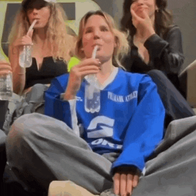 a woman in a blue jersey is drinking through a straw .