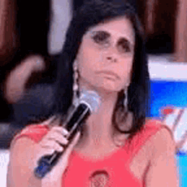 a woman in a red dress is holding a microphone in front of her face .