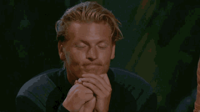 a man with his eyes closed and his hands folded in prayer