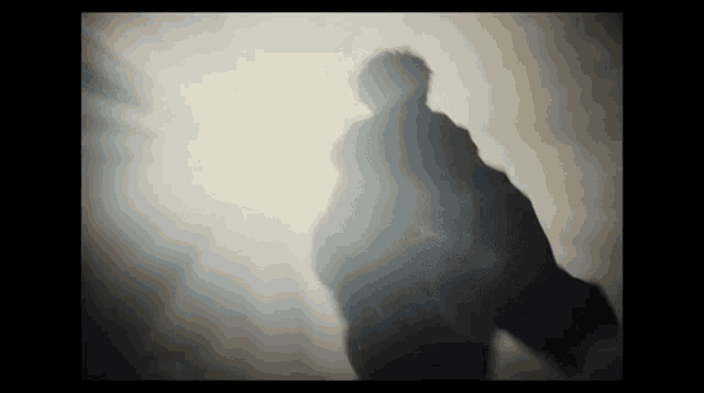 a silhouette of a person in a dark room with smoke coming out of it .
