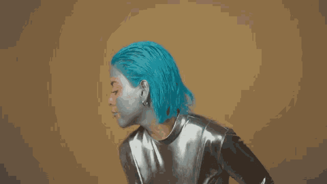 a woman with blue hair and silver paint on her face is wearing a silver outfit .