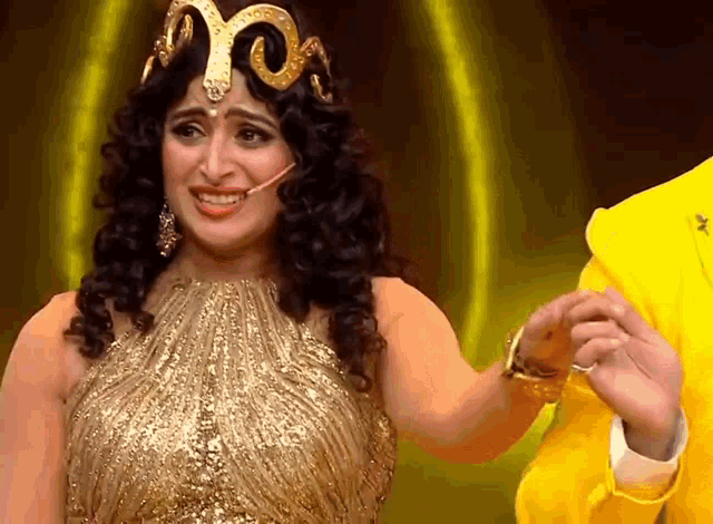 a woman in a gold dress with a snake on her head