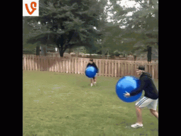 a man is holding a blue ball while another man runs with a ball