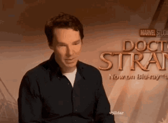 a man is sitting in front of a sign that says doctor strange .