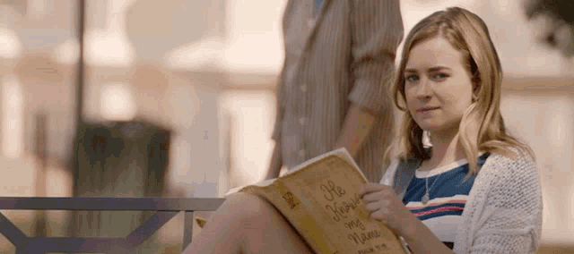 a woman sits on a bench reading a book titled " he knows my name "