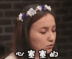 a woman wearing a flower crown on her head is making a funny face with her eyes closed .