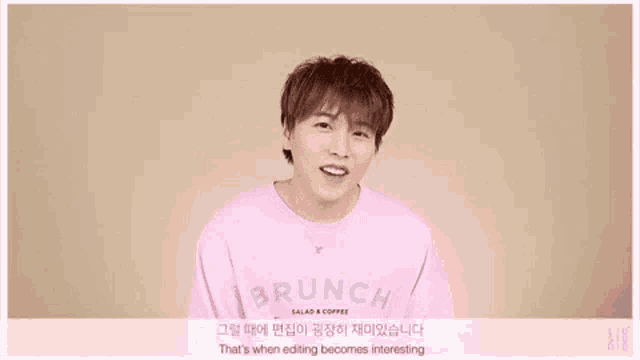 a young man wearing a pink shirt is making a funny face while talking to the camera .