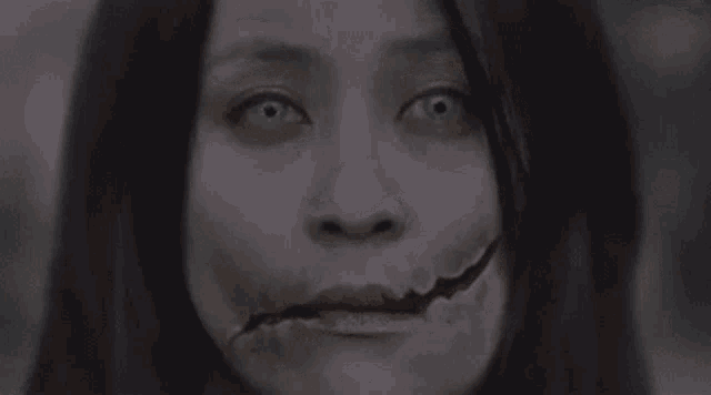 a close up of a woman 's face with a hole in her mouth and green eyes .
