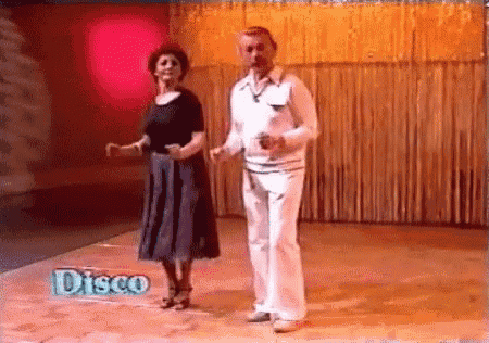 a man and a woman are dancing on a dance floor in front of a sign that says disco