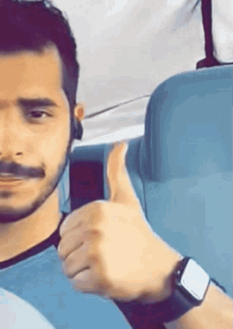 a man wearing a watch is giving a thumbs up