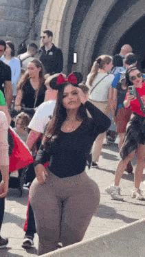 a woman wearing minnie mouse ears is standing in front of a crowd .