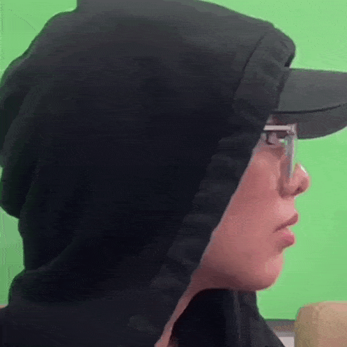 a person wearing a black hoodie and a hat with glasses on .
