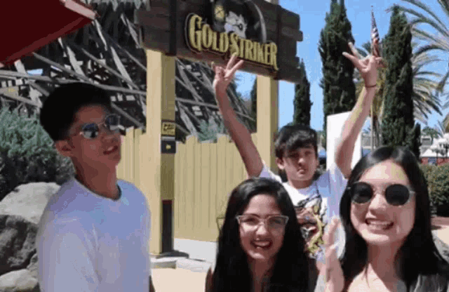 a group of people are posing in front of a gold striker sign