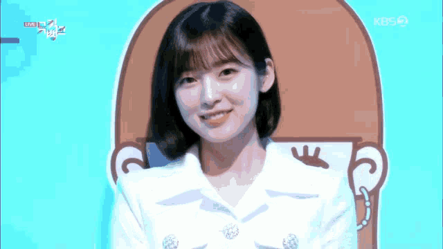 a woman in a white jacket is smiling in front of a picture of a coffee cup ..