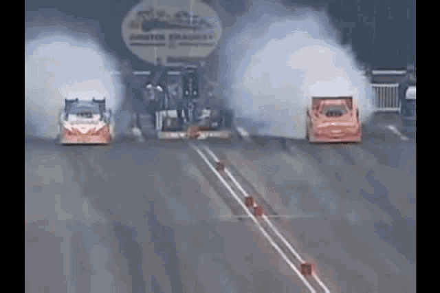 two drag racing cars are on a track with smoke coming out of the engines