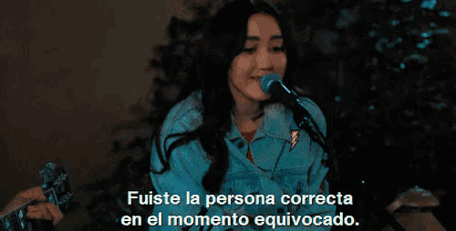 a woman singing into a microphone with the words " fuiste la persona correcta en el momento equivocado " behind her