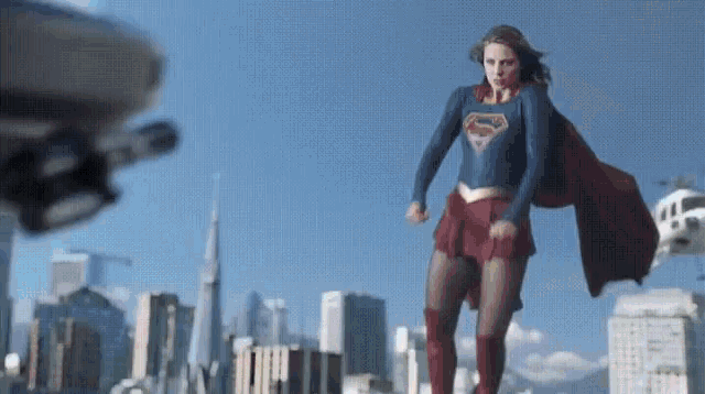 a woman in a superhero costume is standing in front of a city skyline .