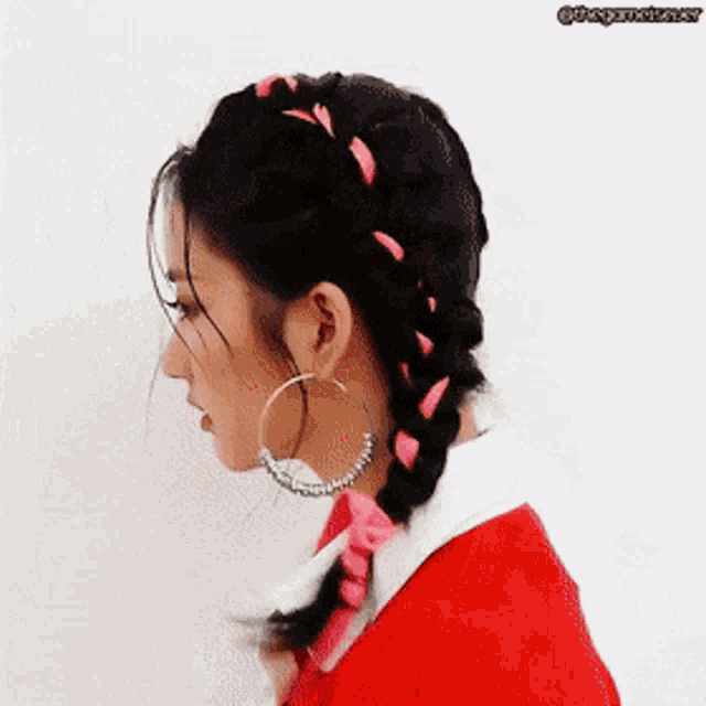 a woman with a braid and hoop earrings is wearing a red jacket
