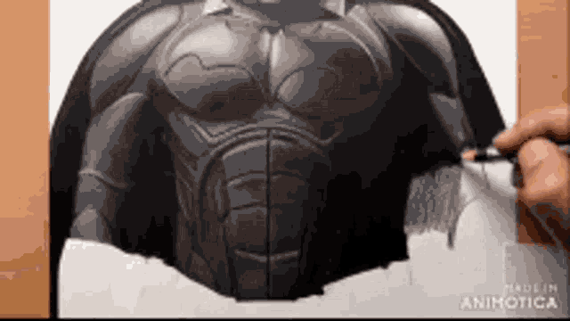 a person is drawing a batman with a pencil on a piece of paper .