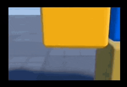 a yellow box is sitting on top of a blue box on a brick floor .