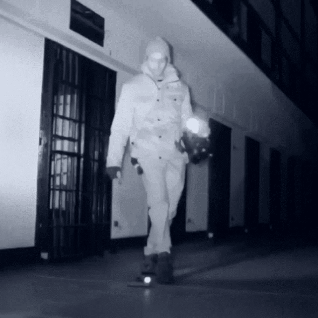 a man in a white jacket is walking in a hallway