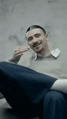a man is sitting on the floor smoking a cigarette and making a funny face .