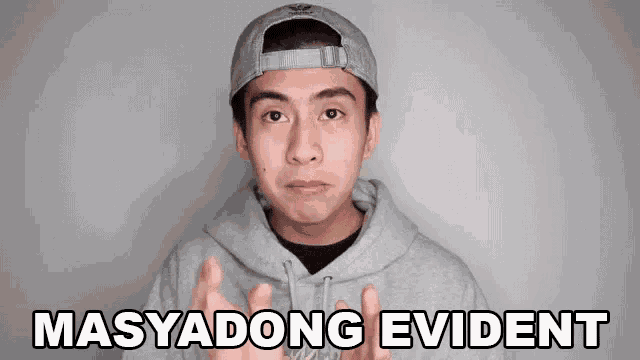 a young man wearing a hat and a hoodie is making a face and says masyadong evident