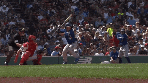 a baseball player wearing a blue jays jersey stands on the field in front of a crowd