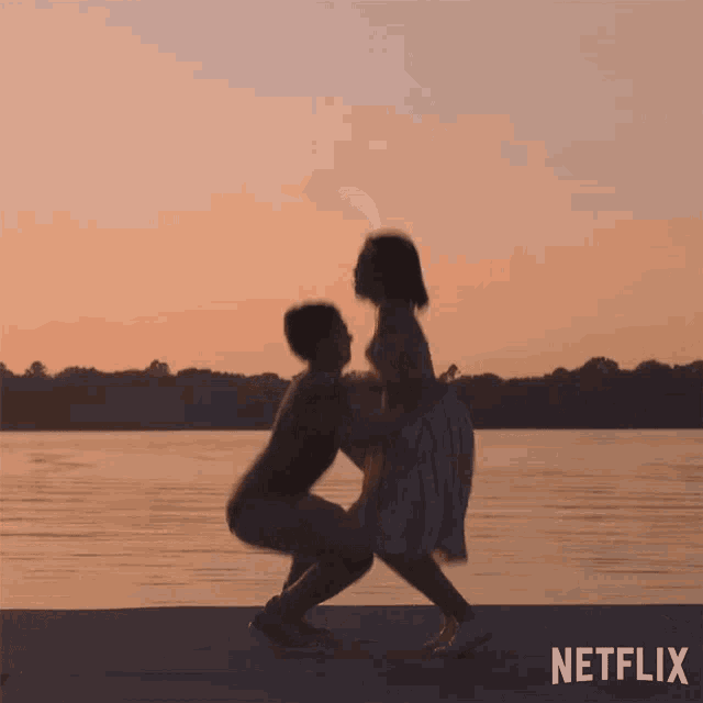 a couple squatting next to a body of water with the netflix logo in the corner
