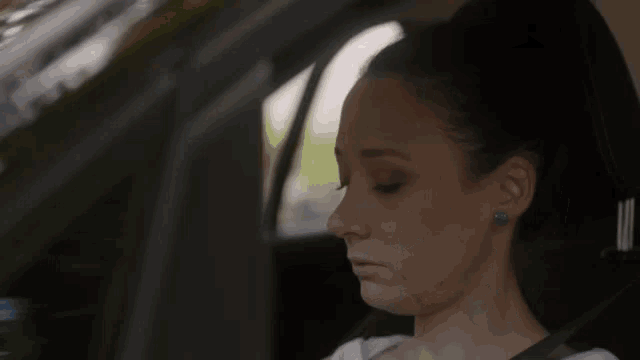 a woman is sitting in the driver 's seat of a car and crying .