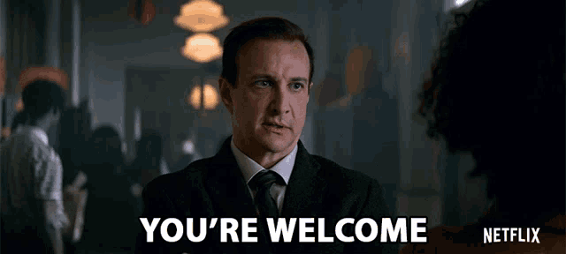 a man in a suit and tie is saying you 're welcome