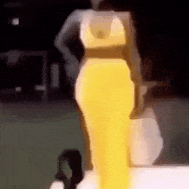 a woman in a yellow dress is walking on a runway .