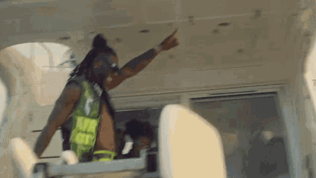 a man with dreadlocks is standing on a boat and pointing at the camera .
