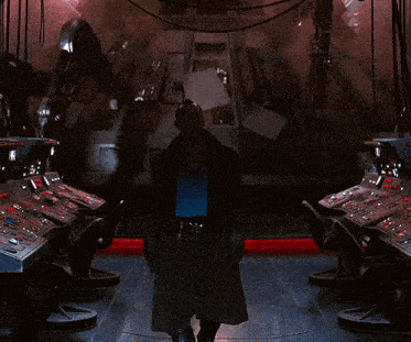 a man in a trench coat is standing in a room with a lot of buttons