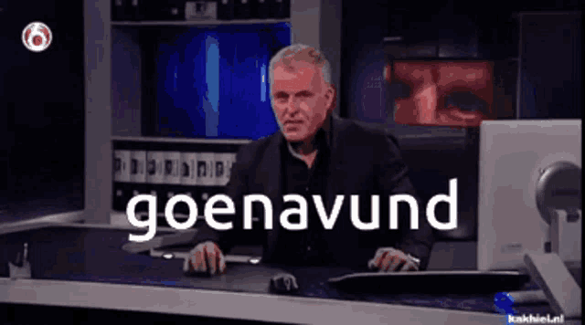 a man sitting at a desk with the word goenavund written on the screen behind him