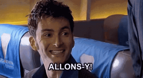 a man is smiling and says allons-y while sitting on a plane .