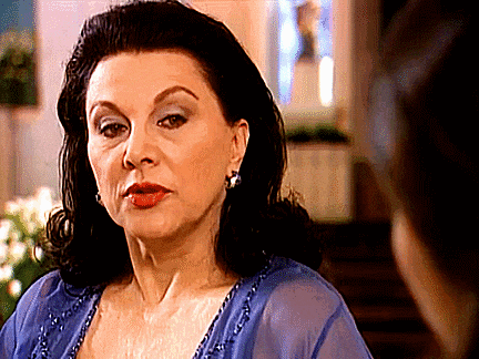 a woman wearing a blue dress and earrings looks at another woman