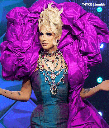 a drag queen is wearing a purple and blue dress and jewelry