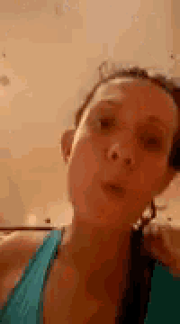 a woman in a blue tank top is making a funny face while looking at the camera .