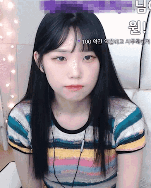 a girl wearing a striped shirt is sitting in front of a screen that says 100 on it