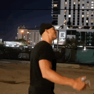 a man in a black shirt is standing in front of a building that says ' hotel ' on it
