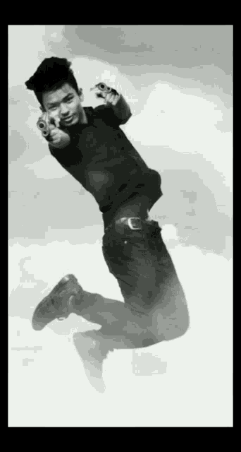 a man in a black shirt is jumping in the air with two guns pointing at the camera