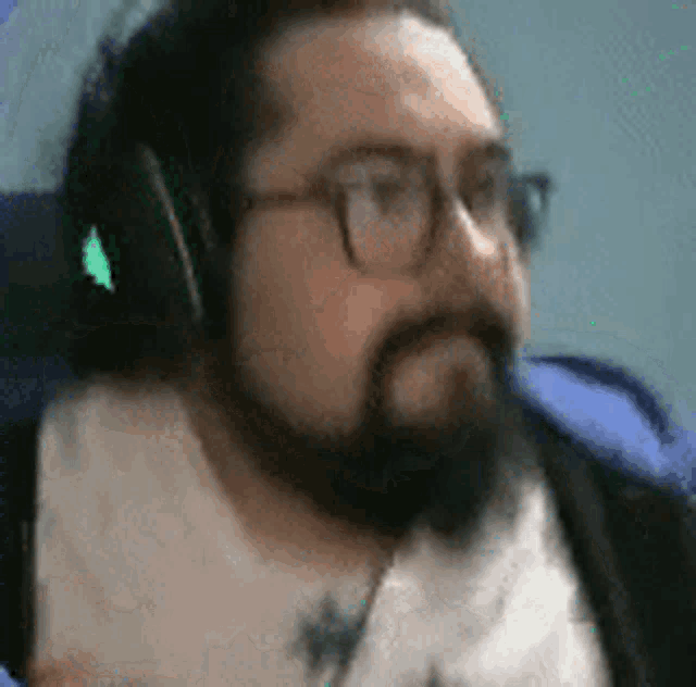 a man with a beard and glasses wearing headphones .