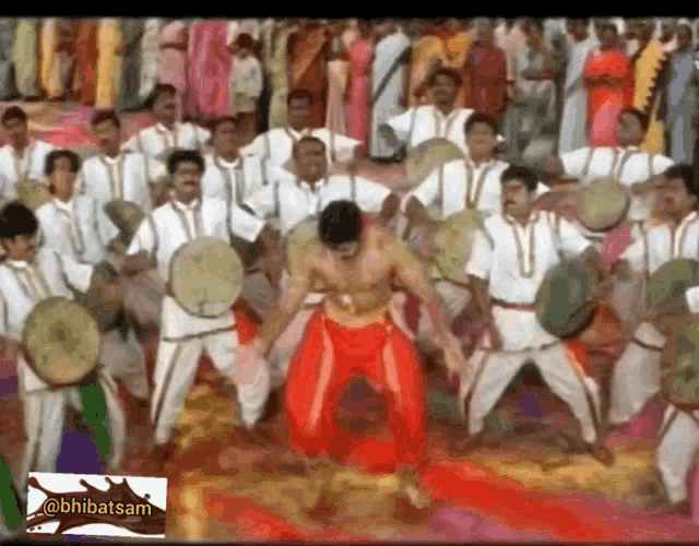 a man without a shirt is dancing in front of a crowd with drums