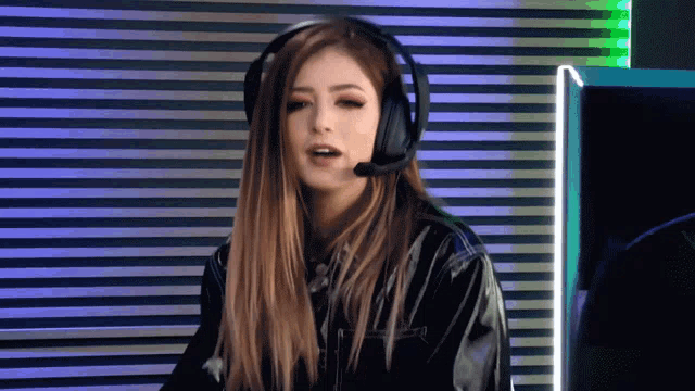 a woman wearing headphones and a microphone is sitting in front of a computer monitor